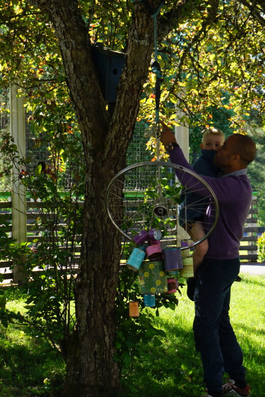 Barn og voksen under et tre på lekeplass